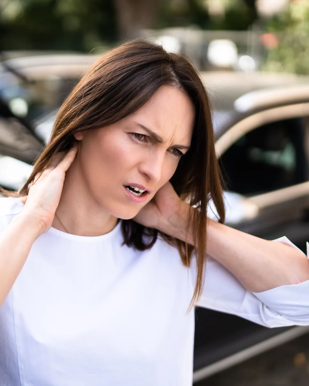Woman holding her neck after stiffness from a car accident, a common whiplash sign